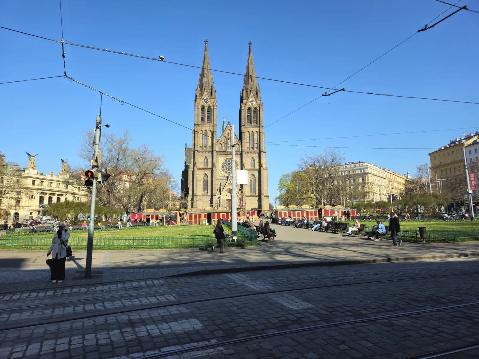 The twin spires of the Church of St Ludmila above the park on Náměstí Míru in Vinohrady, with tram tracks and overhead wires in front