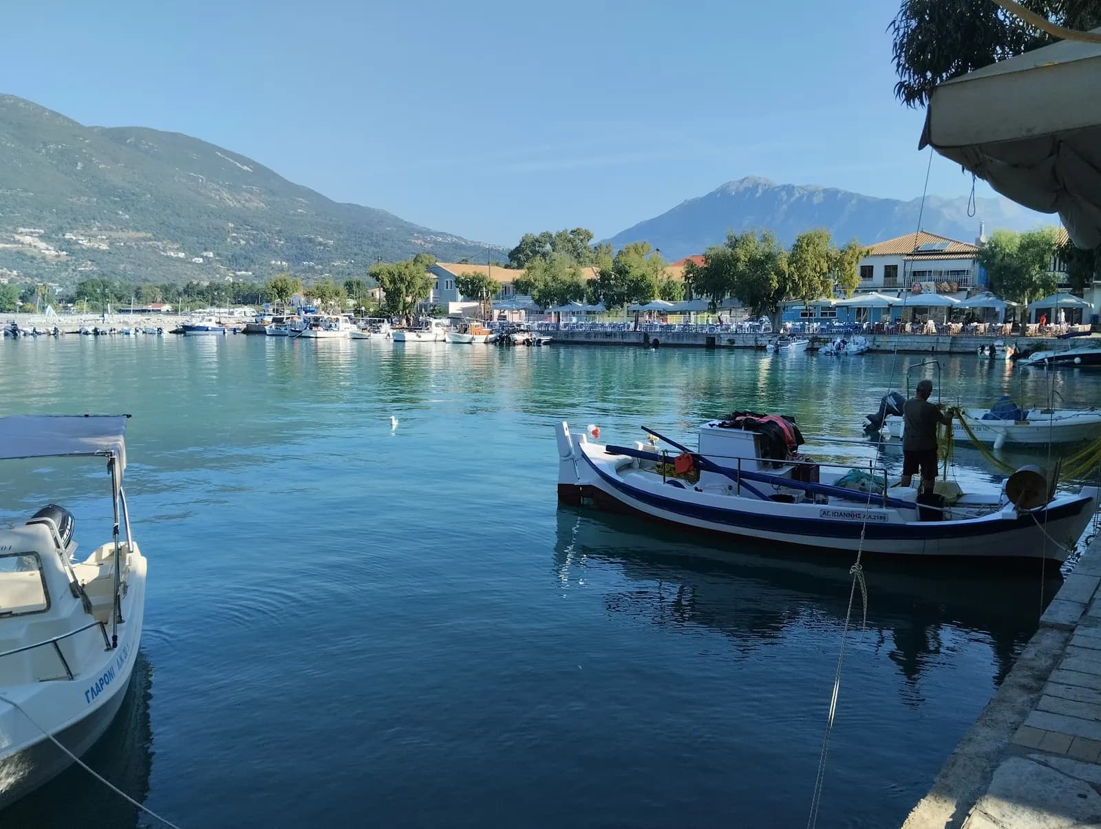 The harbour of Vasiliki on the south coast of Lefkada, with small fishing boats in calm water, waterfront tavernas and mountains behind
