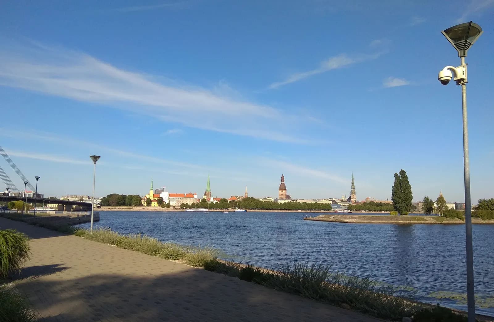 The church spires of Old Riga seen across the Daugava from the Āgenskalns bank, with a riverside path in front
