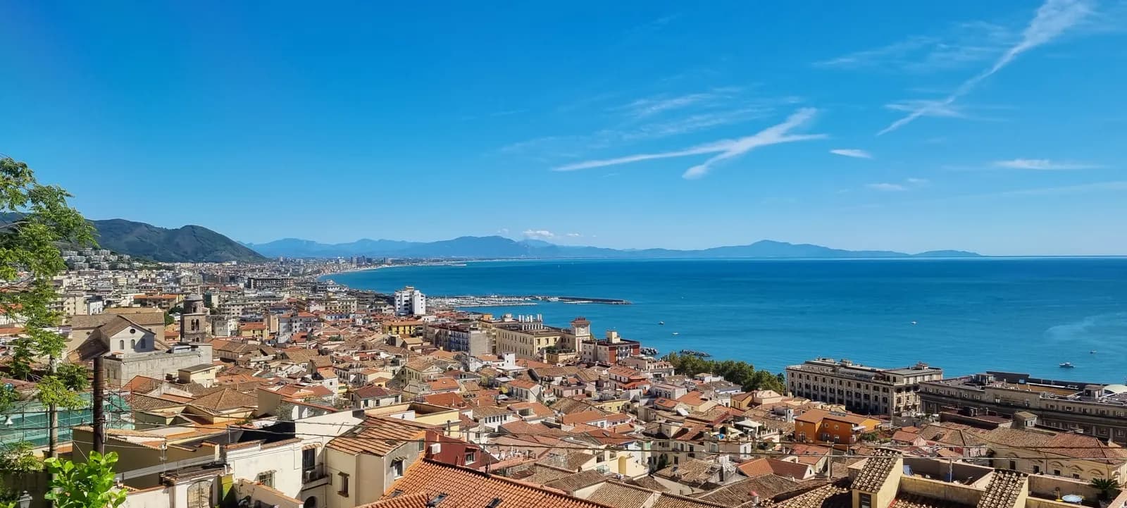 The terracotta rooftops of Salerno's old town seen from the hill below the Castello di Arechi, with the seafront, the port and the Gulf of Salerno behind.