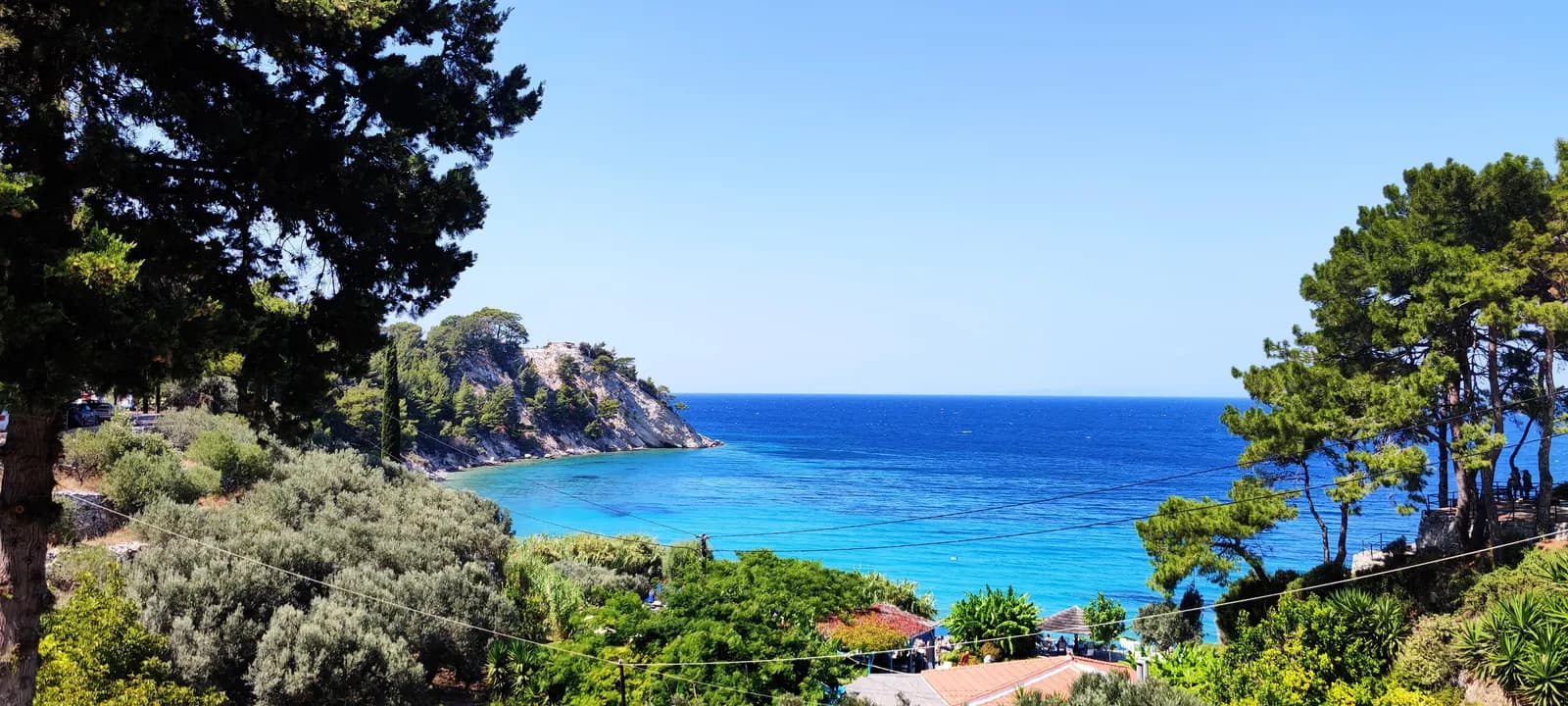 Turquoise water in the bay at Lemonakia near Kokkari, framed by pine trees and a rocky headland