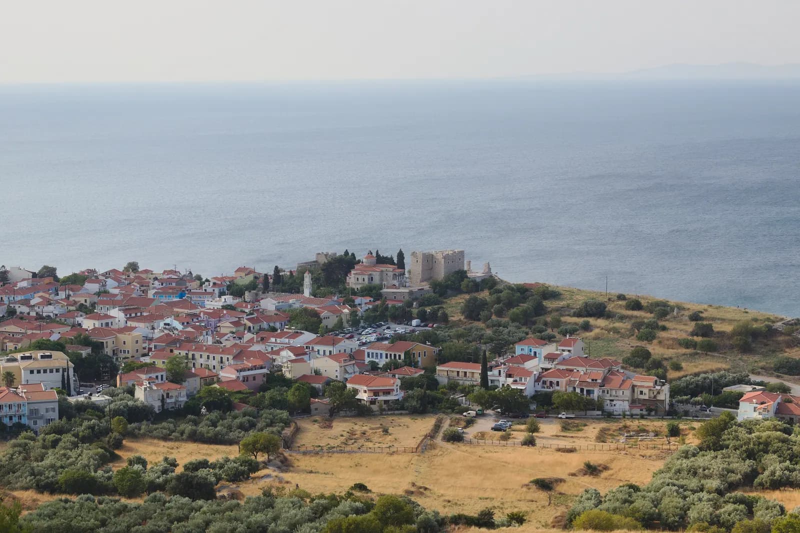 Pythagoreio from the hillside above, with red-roofed houses, the stone castle tower and the sea behind