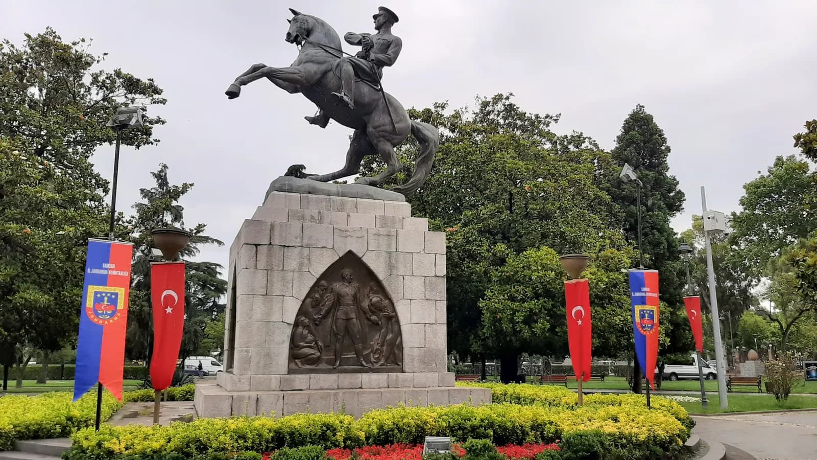 The equestrian Onur Monument in central Samsun on its stone plinth, with flags and flower beds around it