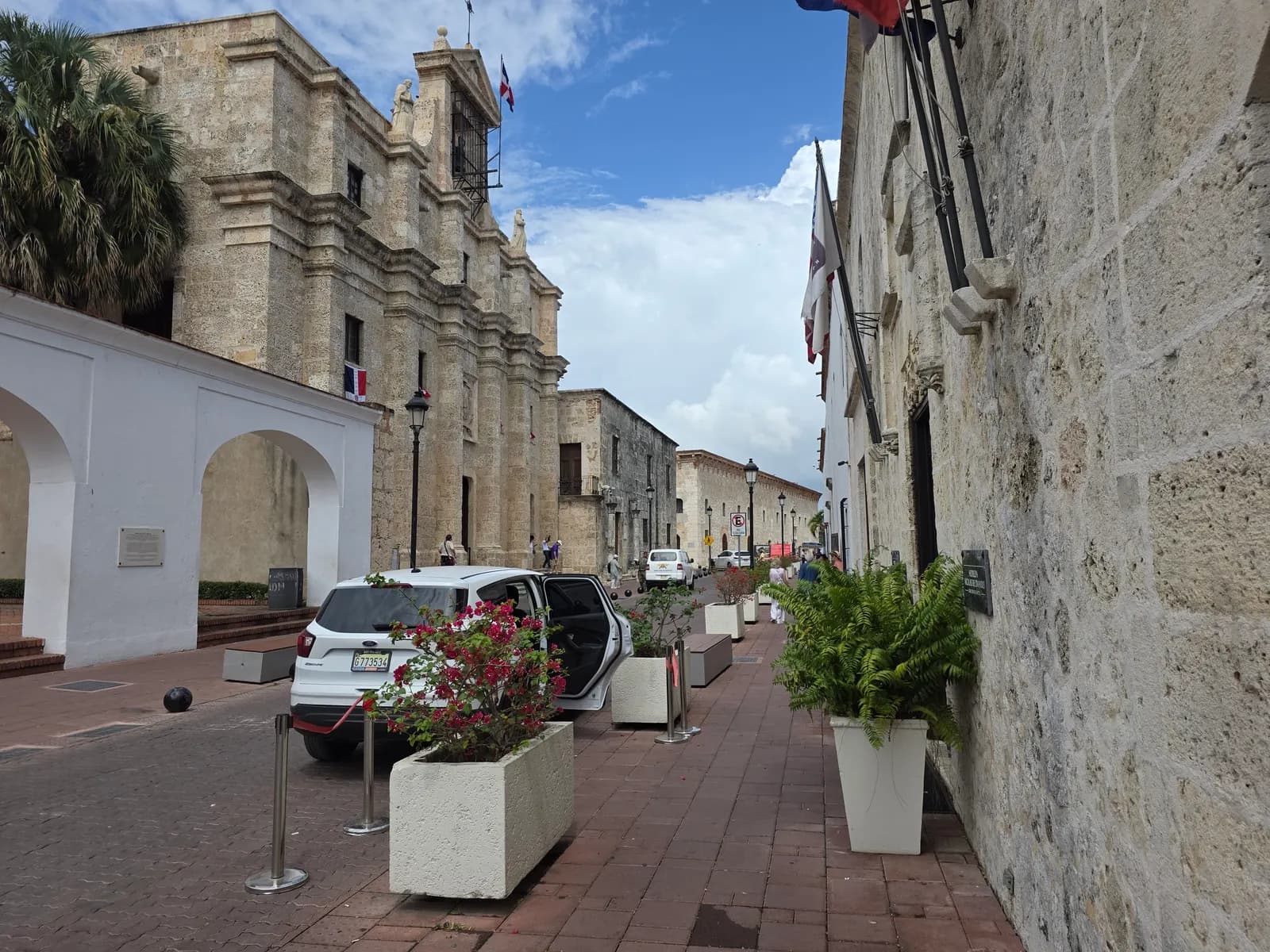 Calle Las Damas in the Zona Colonial, a brick-paved street between stone colonial buildings, with planters, bollards and a parked white car