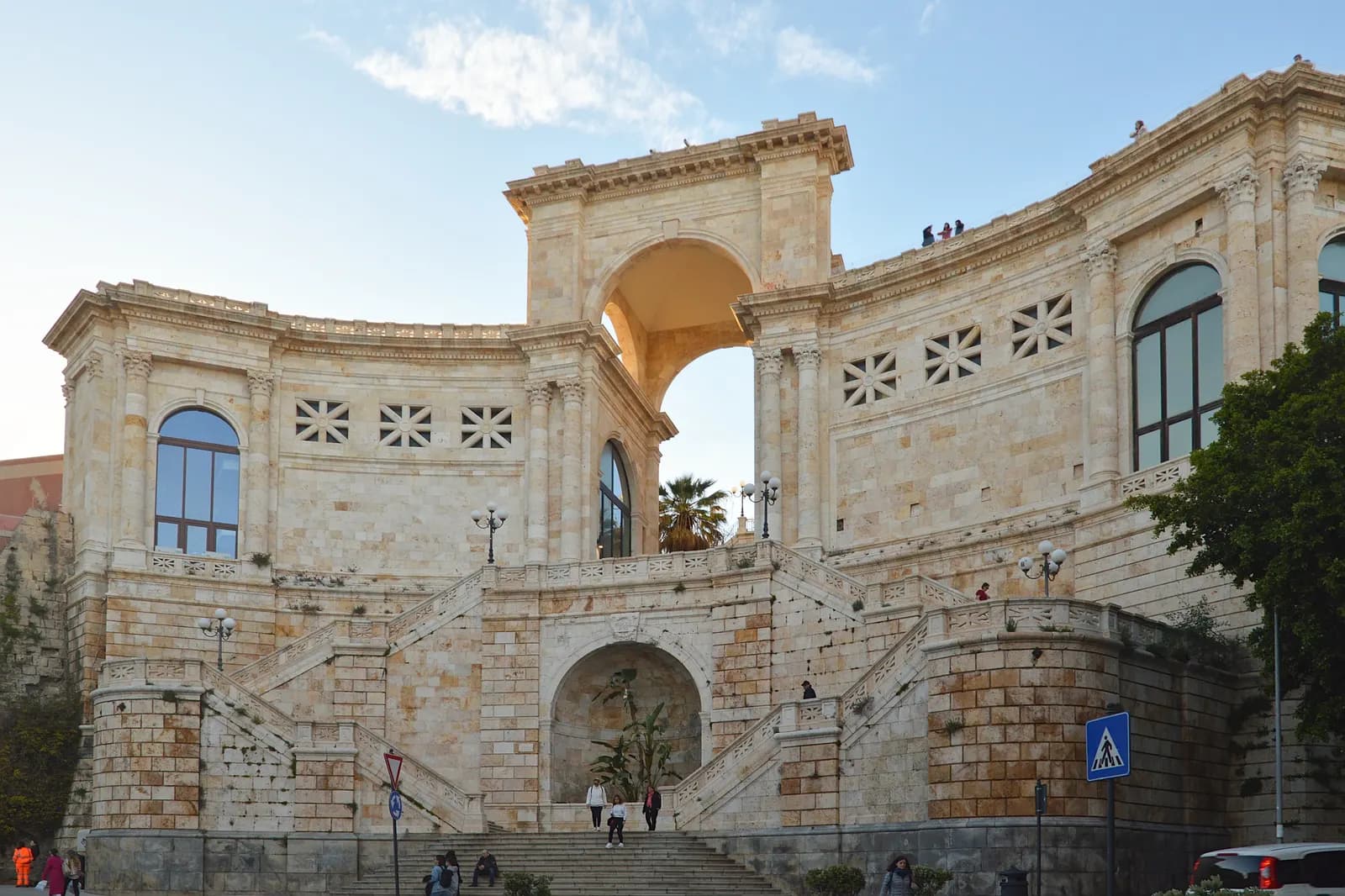 The Bastione di Saint Remy in Cagliari, a pale limestone terrace with a central arch and a double staircase, under a blue sky