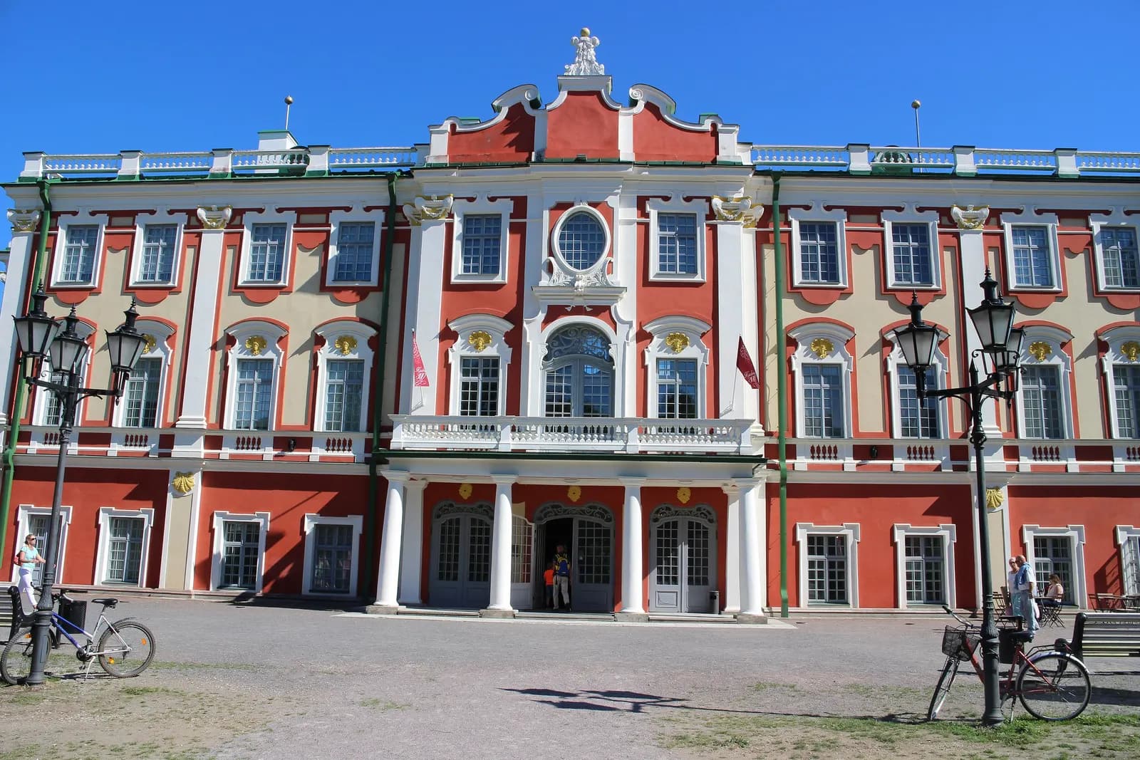The red and white Baroque façade of Kadriorg Palace in Tallinn, with bicycles and lamp posts in front