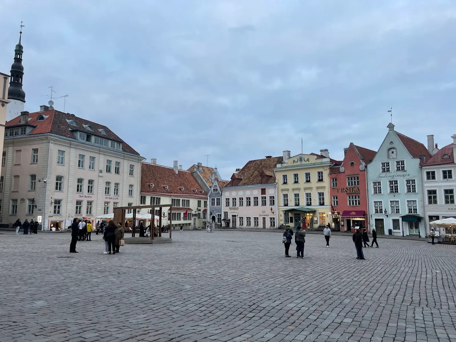 Raekoja plats, the Town Hall Square of Tallinn Old Town, with pastel merchant houses around the cobbled square under a grey sky