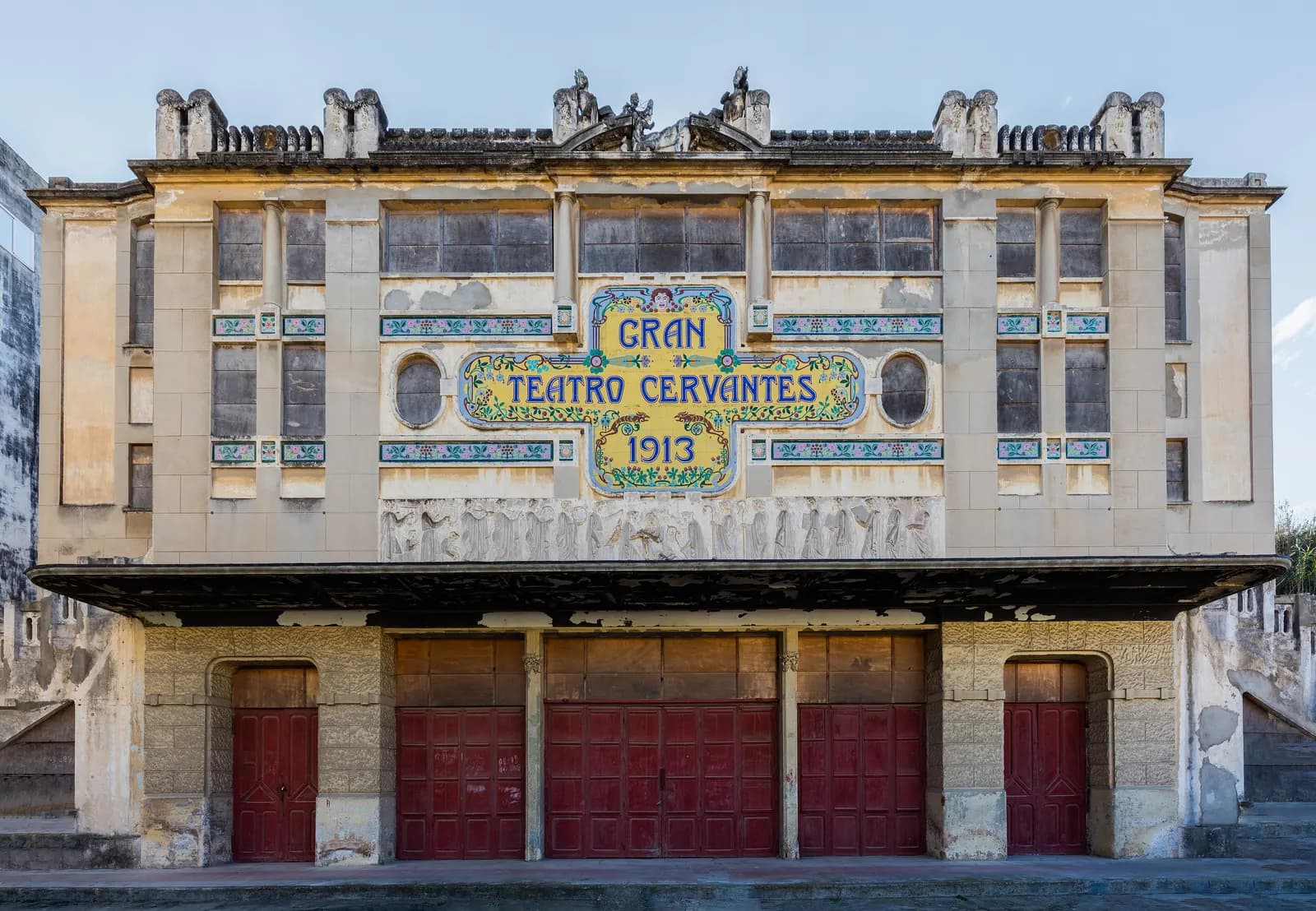 The front of the Gran Teatro Cervantes in Tangier, its name and the year 1913 in blue letters on a panel of yellow tiles above a row of red doors