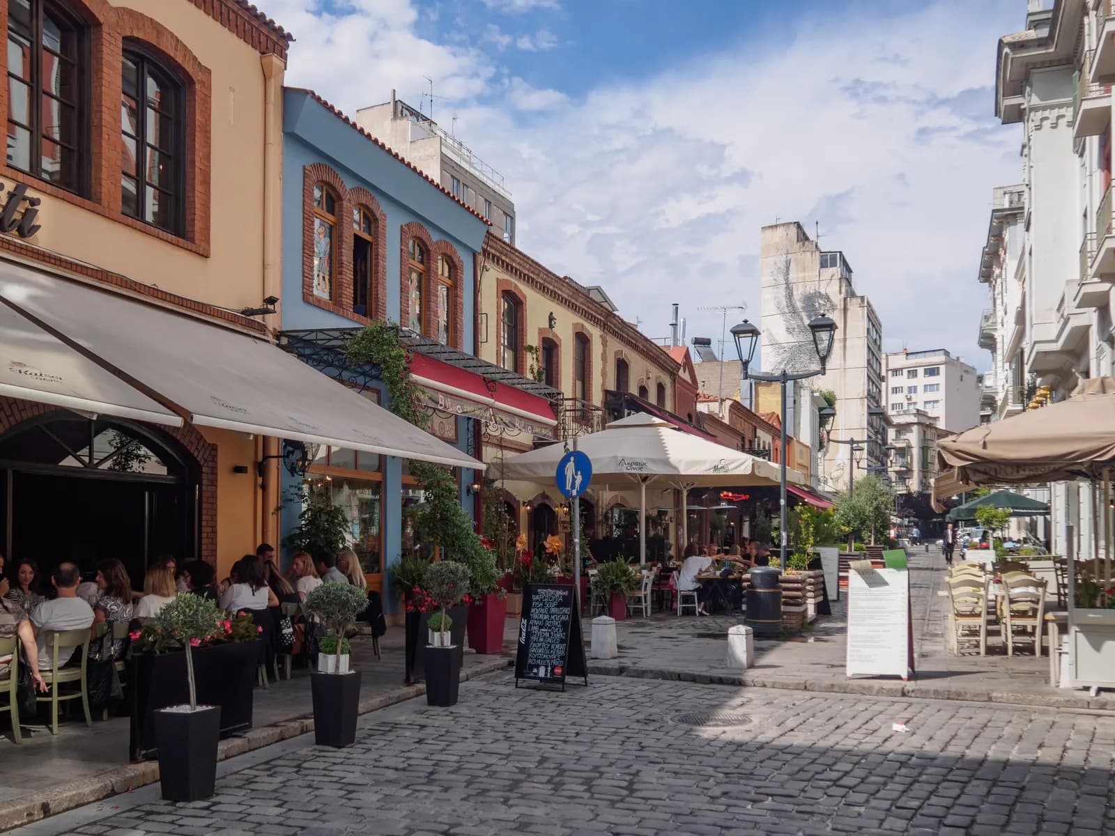 Cafe and restaurant terraces under awnings on the cobbled Katouni Street in the Ladadika quarter of central Thessaloniki