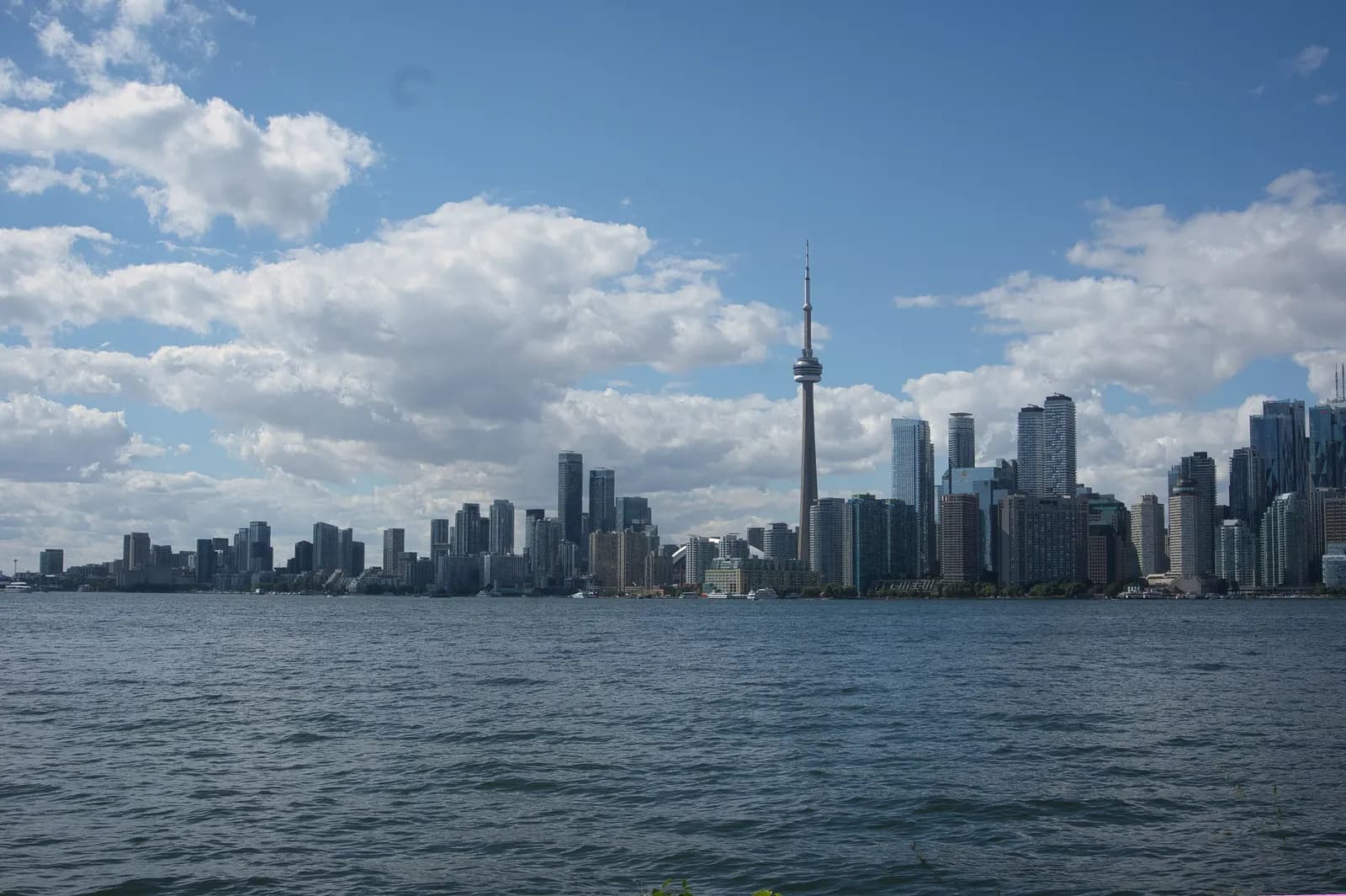 The Toronto skyline with the CN Tower seen across the water of the harbour from Algonquin Island, under white clouds