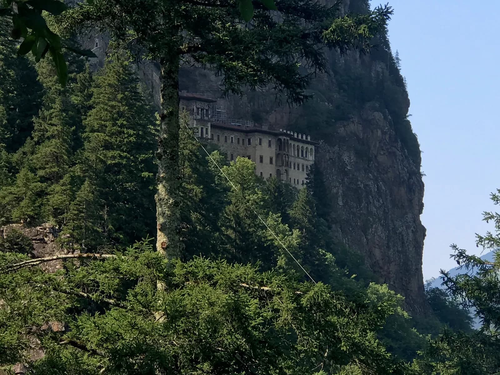 Sumela Monastery seen through fir trees on the wooded slopes of the Altındere valley