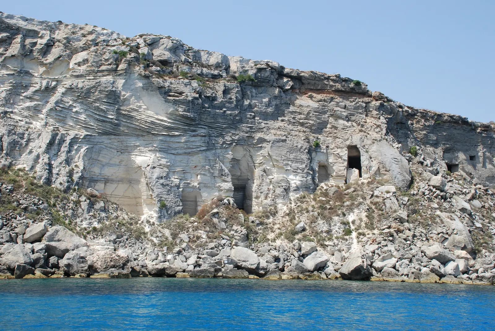 The cut tufa cliffs above the blue water at Cala Rossa on Favignana, with old quarry faces in the rock