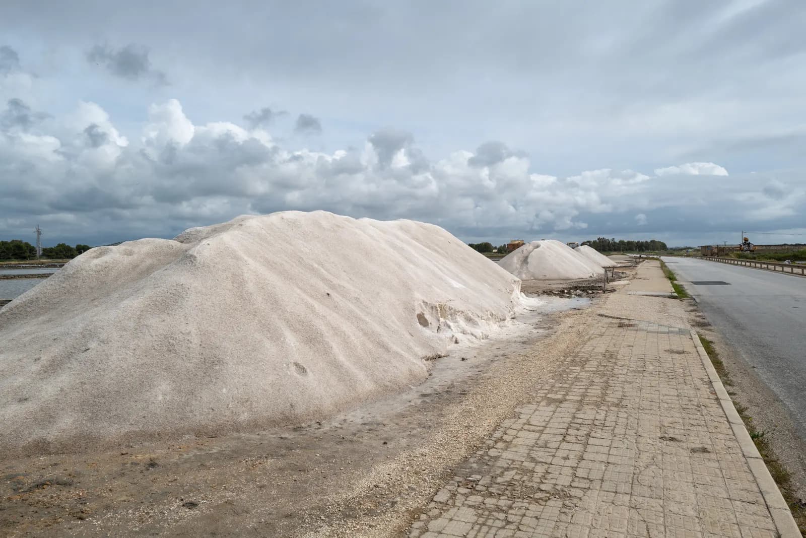Heaps of harvested sea salt beside the road through the salt pans of Trapani and Paceco