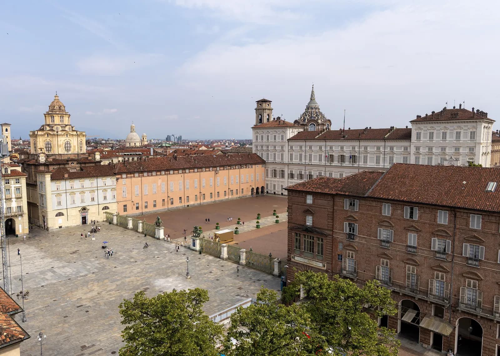 Piazza Castello in Turin seen from above, with the dome of San Lorenzo, the white facade of the Royal Palace and the paved square and Piazzetta Reale below.
