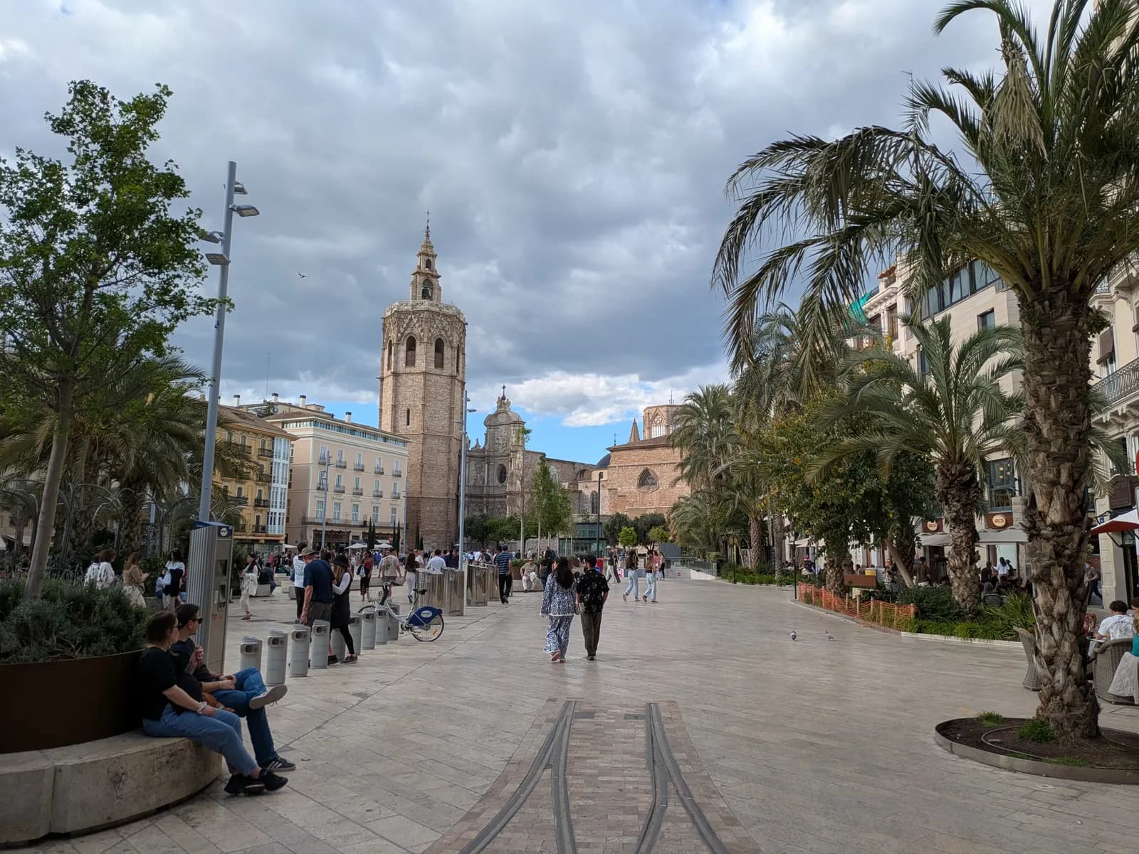The pedestrianised Plaça de la Reina with palm trees and the Micalet bell tower of Valencia Cathedral at the far end.
