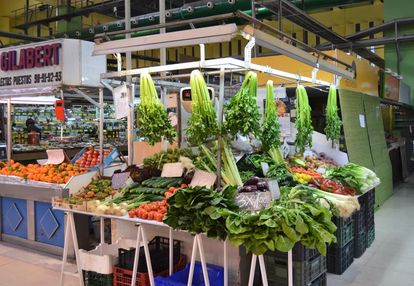 A greengrocer stall in the Russafa market stacked with celery, tomatoes and leafy vegetables.