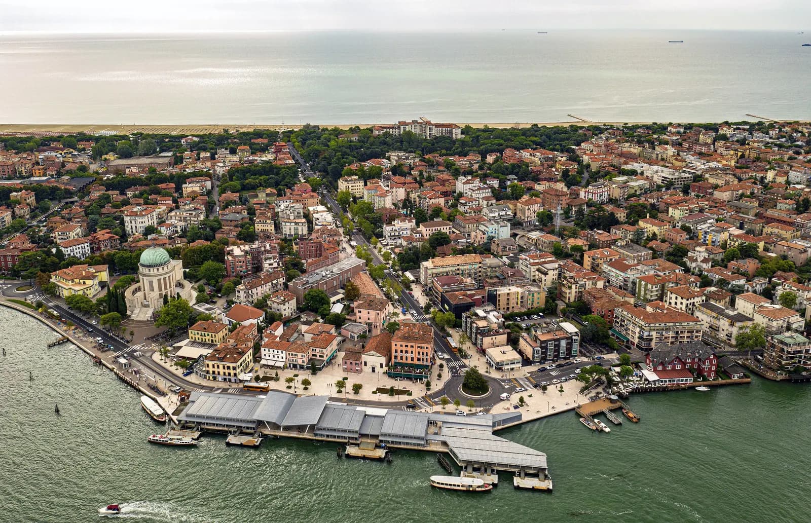 An aerial view across the Lido di Venezia, from the Santa Maria Elisabetta boat terminal on the lagoon over streets of hotels and houses to the Adriatic shore.