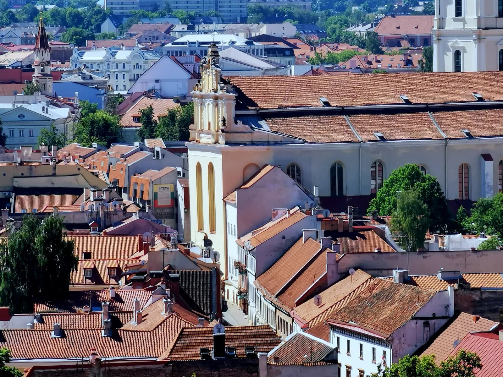 Tiled roofs and church façades of Vilnius Old Town around Pilies street, seen from above