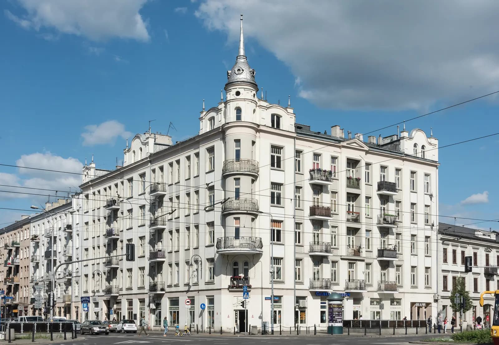 A white corner tenement with balconies and a spire at Ząbkowska 2 in Warsaw's Praga district under a blue sky