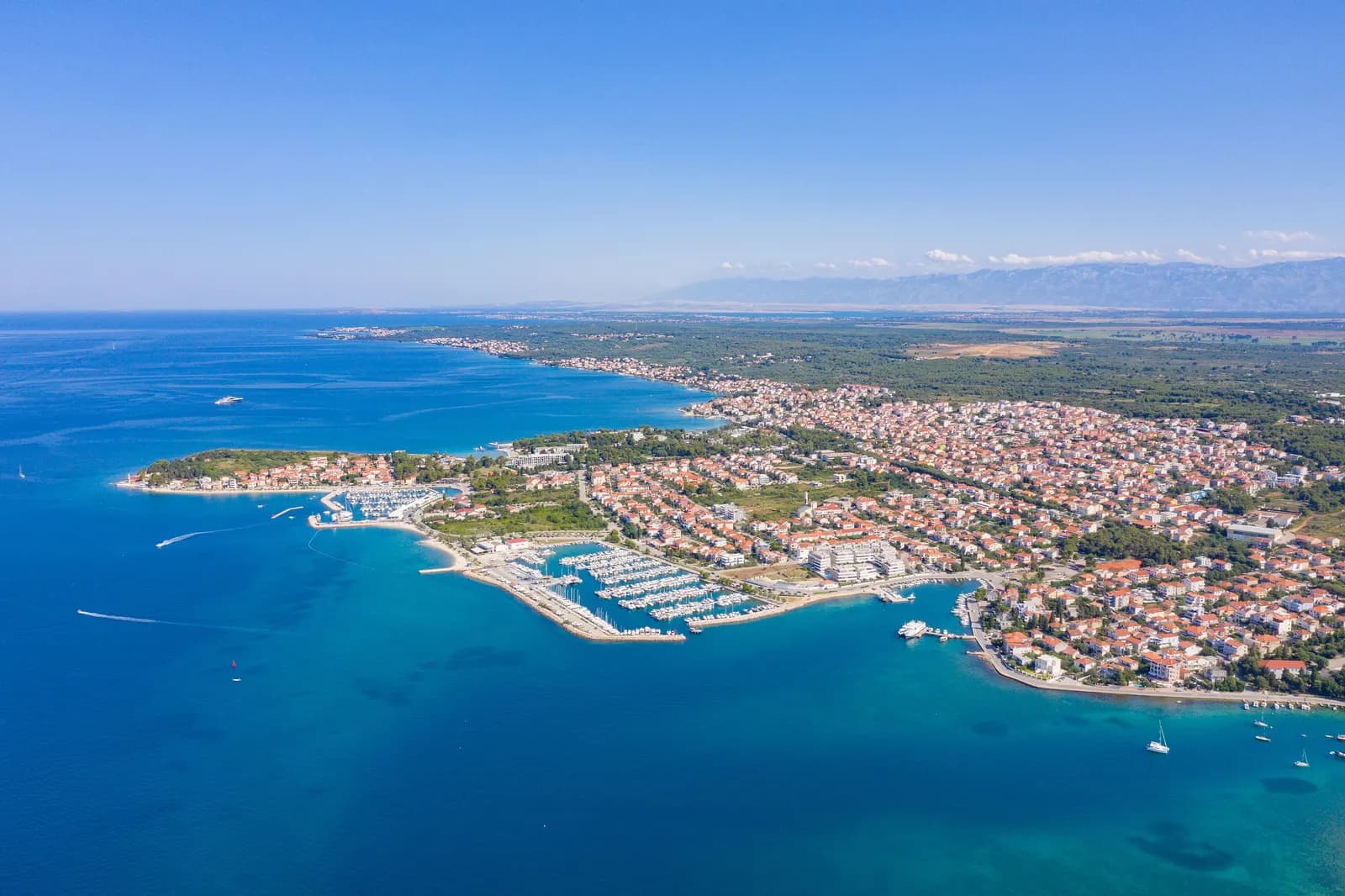 Aerial view of Zadar's north-western shore with the Puntamika headland, two marinas, low-rise houses and the coast running on north-west below the Velebit range